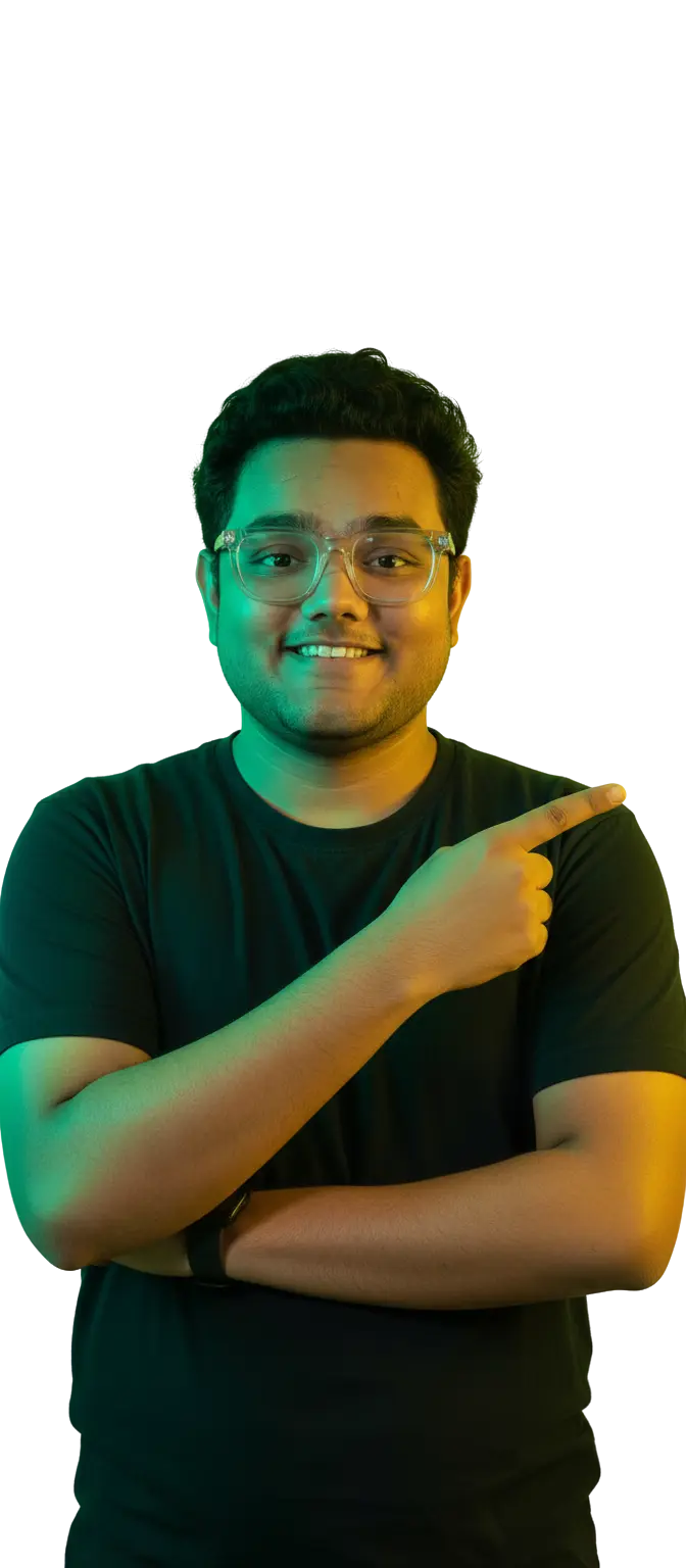 Portrait of Dhruv Gehlot, a young man smiling and pointing confidently to the right. He wears glasses and a black t-shirt, illuminated by vibrant green and yellow light against a light gray background.