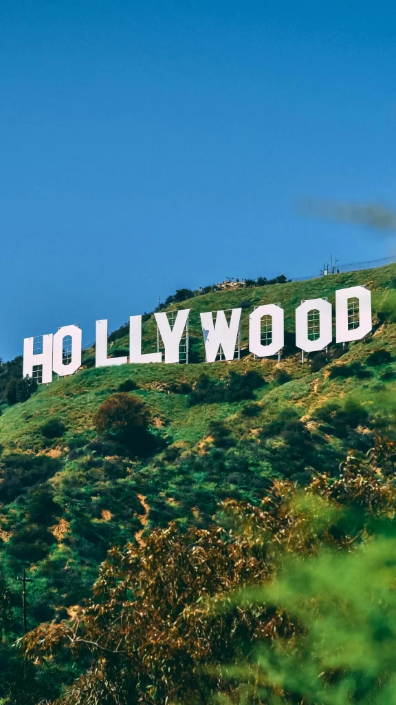 Iconic Hollywood sign on a grassy hillside under a clear blue sky.